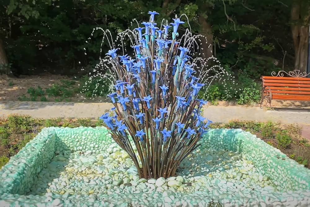 blue flowers and metal fountain Art installation in the garden blue flowers and metal fountain Art installation in the garden