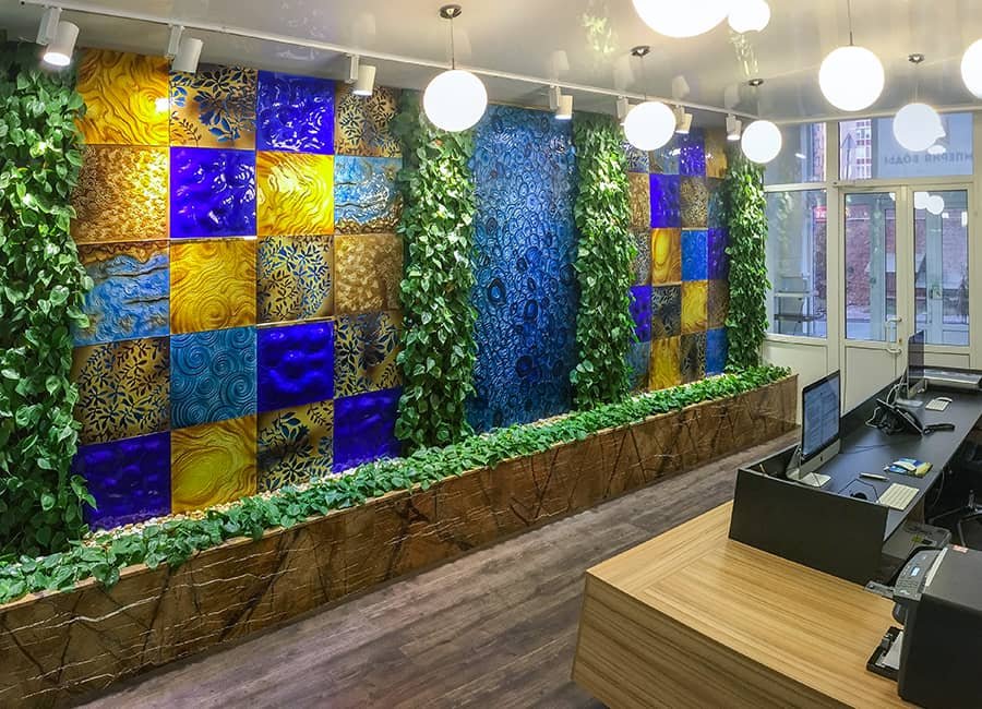 Custom hand-blown glass art wall with blue and gold panels, integrated living green plants, interior feature for commercial space custom decorative glass wall installation with living plants