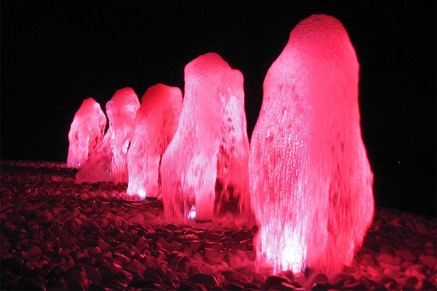 Illuminated Foam Jet Water Feature illuminated foam water jets glowing in pink light on white stones at night