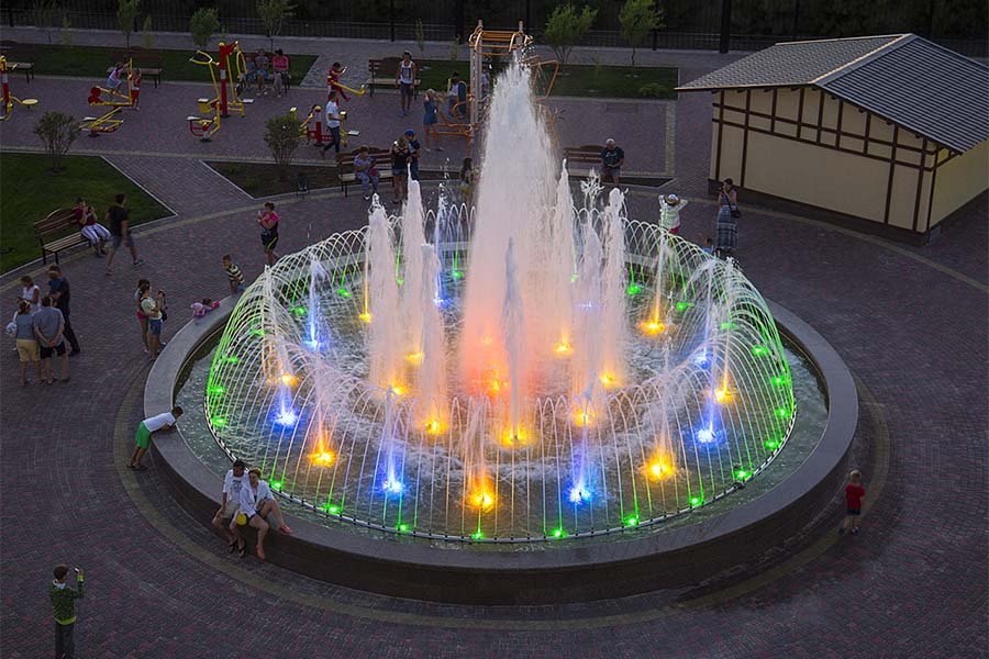 Central plaza illuminated fountain with high vertical water feature Large park illuminated fountain with central geyser-style water jet