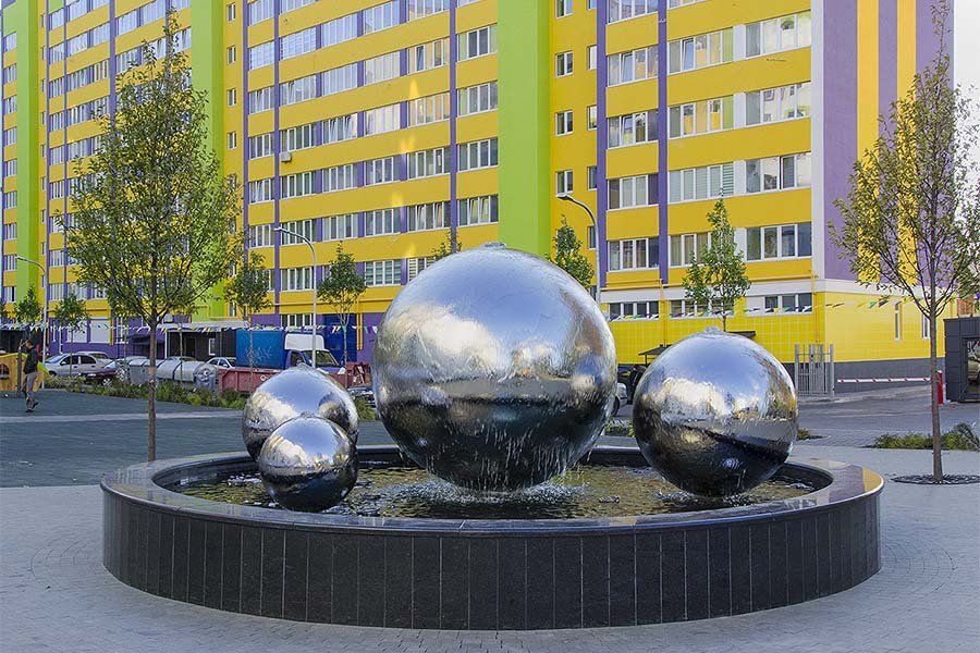 Modern fountain with reflective stainless-steel sphere sculptures in a residential courtyard. Modern fountain with reflective stainless-steel sphere sculptures