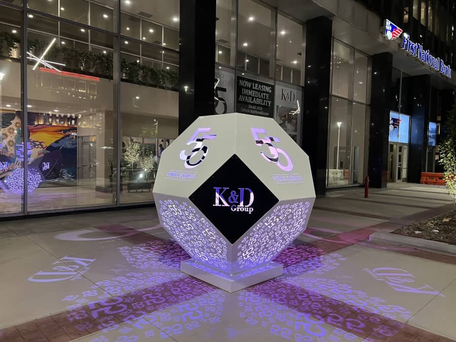 Illuminated geometric public art installation with custom logo and projected light patterns Illuminated geometric art installation with custom logo