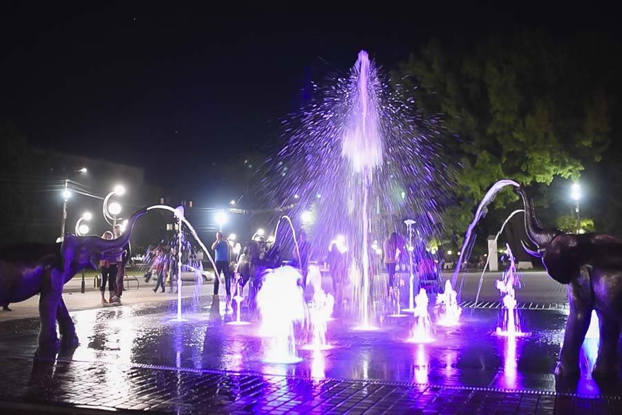 Interactive public fountain installation with dynamic LED lighting and sculptural elements for urban plazas and municipal landscape projects Interactive LED fountain with elephant sculptures at night