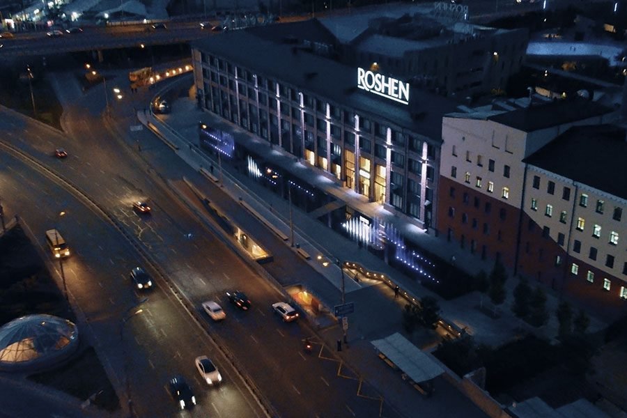 Aerial night view Aerial night view of the ROSHEN building in Kyiv with illuminated facade and dry deck fountain installation along the street