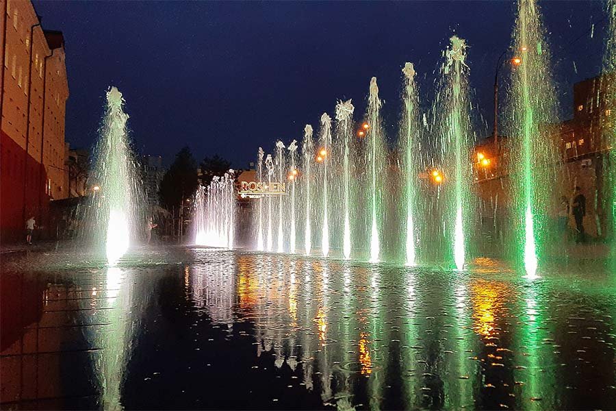 green illuminated water jets Dry deck fountain in Kyiv with white and green illuminated water jets at night reflecting on the surface