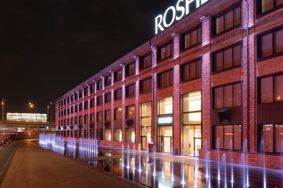 glowing jets fountain ROSEN building in Kyiv illuminated with pink facade lighting and dry deck fountain glowing in front