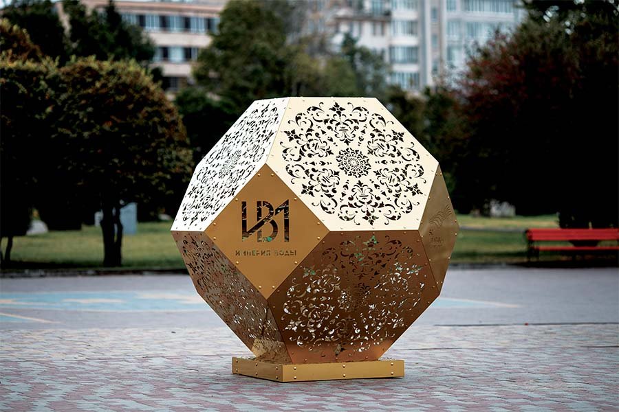 geometric metal sculpture with floral cutout patterns in a public park geometric metal sculpture with floral cutout patterns
