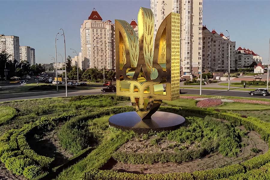 monumental golden Tryzub sculpture installed in an urban roundabout contemporary unique public art sculpture