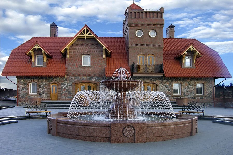 Tiered Granite Fountain in Front of Country House Classic tiered granite fountain with radial water jets in front of a large country house