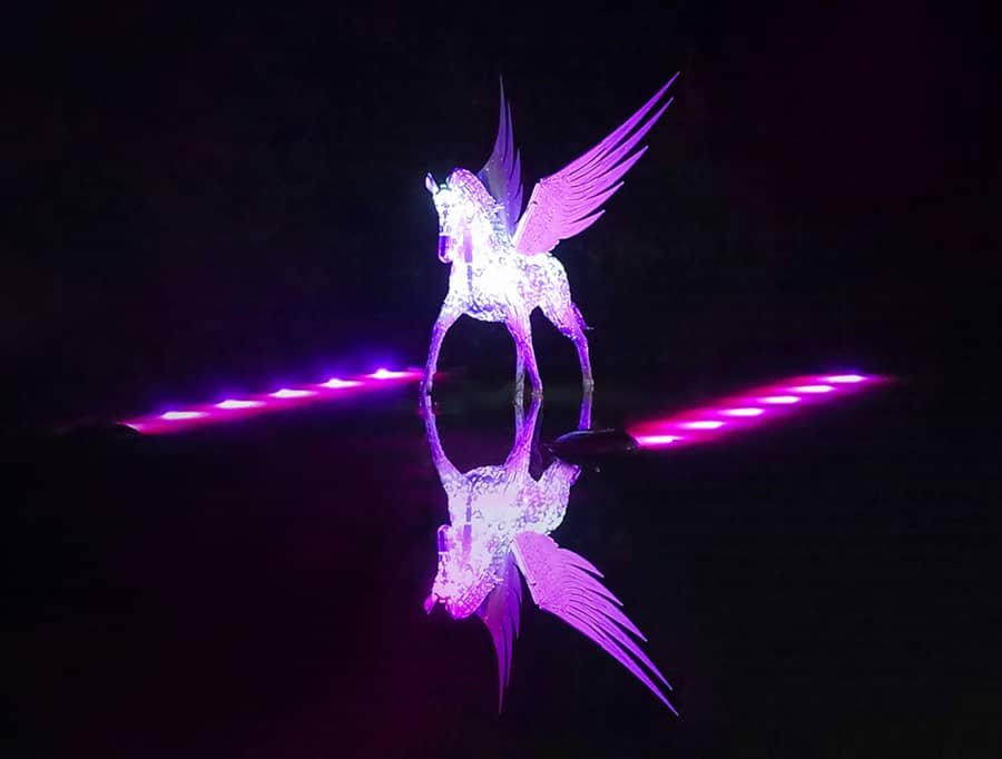 Illuminated winged horse art installation with reflection