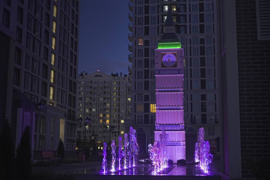 illuminated clock tower art feature in residential plaza