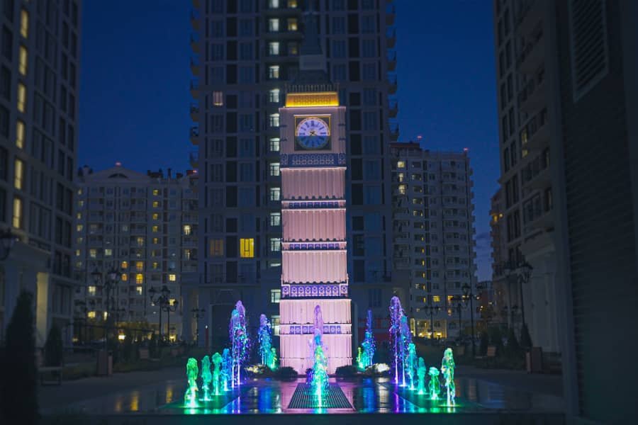 illuminated fountain with clock tower at night