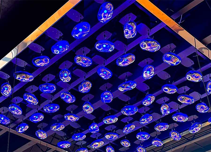 Kinetic glass art installation with illuminated hanging elements