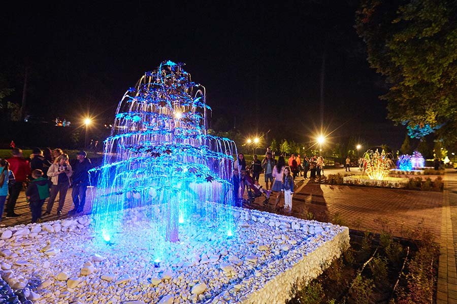 metal tree art feature with water and light at night