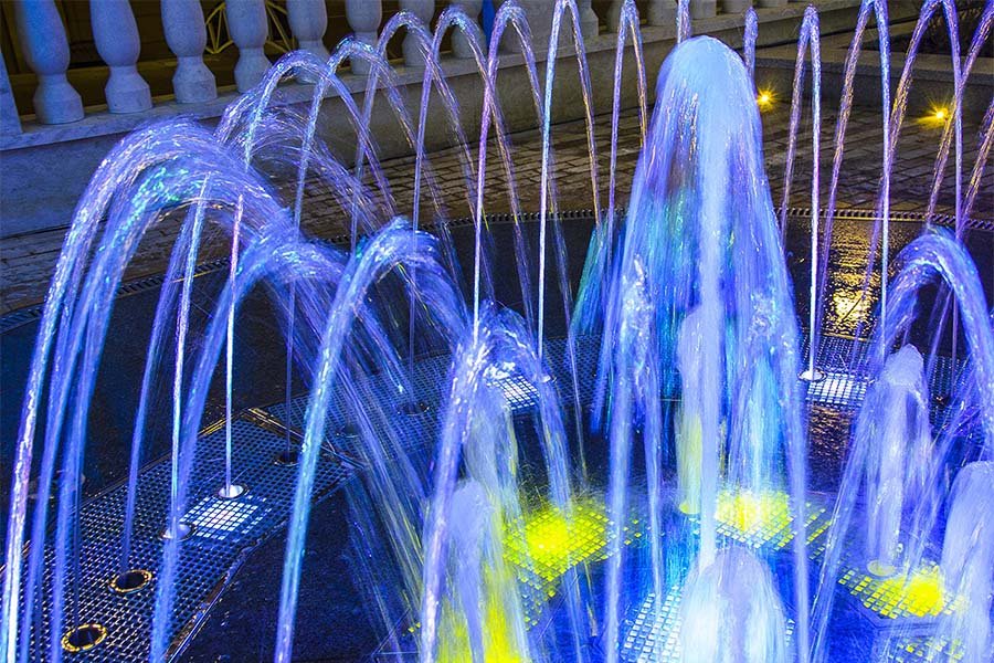 Interactive dry deck fountain with RGB LED lights at night