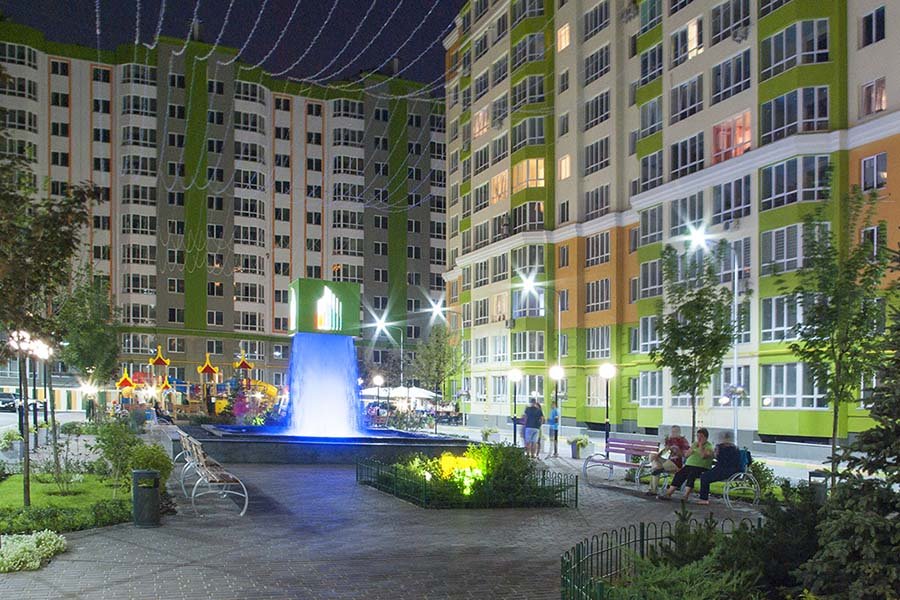 Night courtyard of a residential complex with an LED cube waterfall at the center
