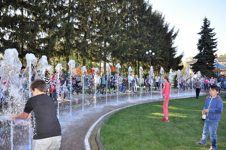 Children playing among linear ground water jets in a public park