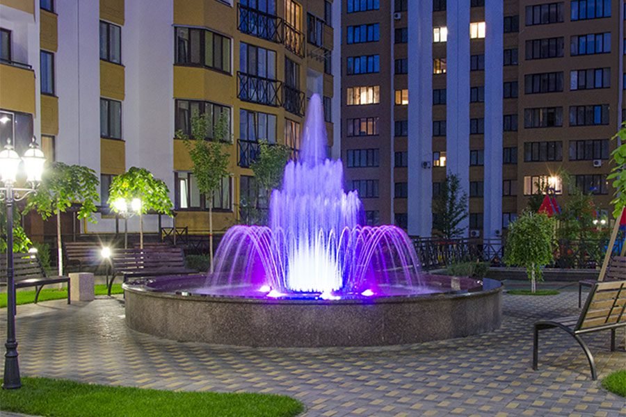 Courtyard fountain with LED-illuminated water jets in a residential complex