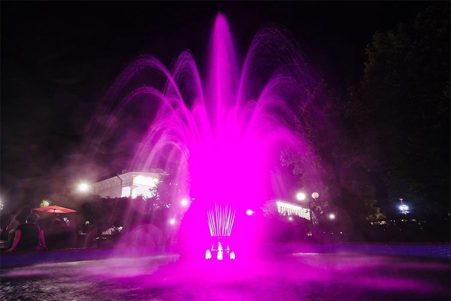 pink LED fountain with water jets at night