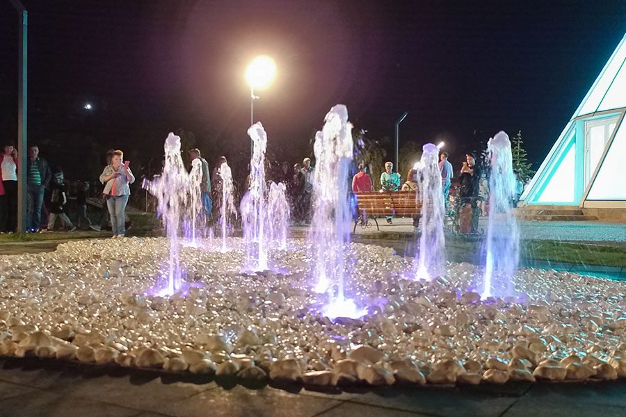 Illuminated ground jets with soft green LED light on decorative stones in a night park