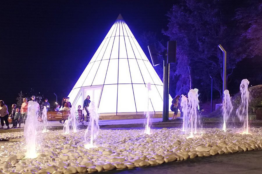 Architectural ground-level fountain with vertical jets and purple LED illumination at night