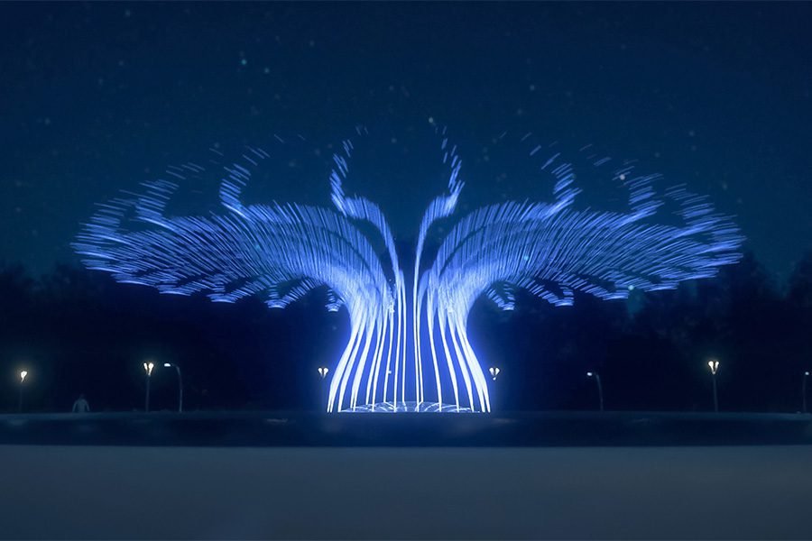 Illuminated fountain creating a dynamic wing-shaped water pattern at night