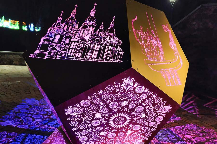 Illuminated geometric metal sculpture with architectural engravings and floral laser-cut patterns