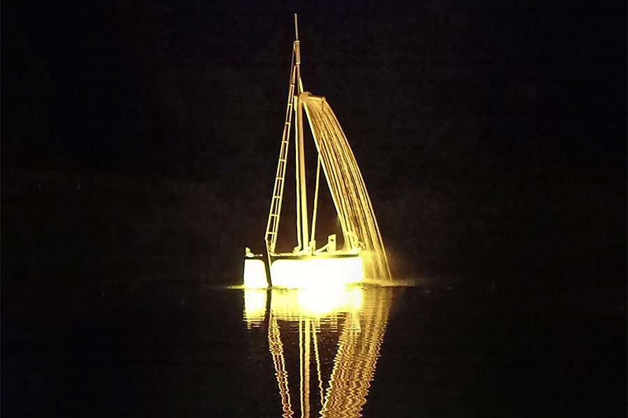 Golden LED sailboat fountain at night