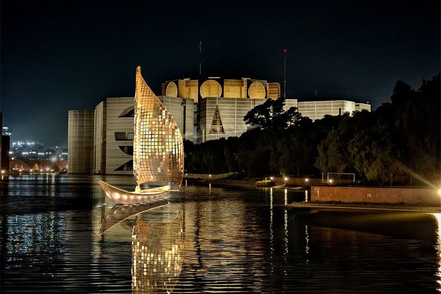 Golden sail sculpture on water