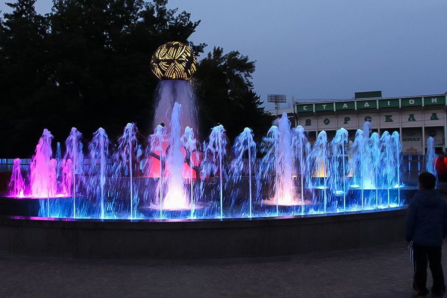 RGB LED fountain with multiple water jets and a central sculpture at night