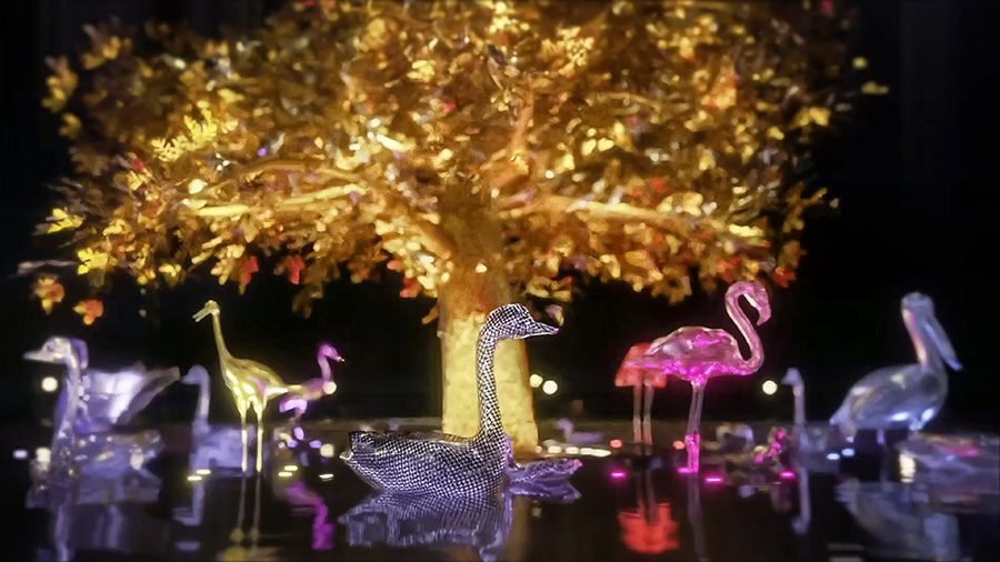 metal swan sculpture in front of golden tree