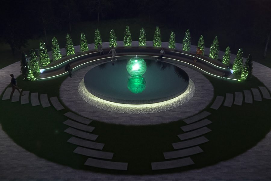 illuminated green sphere fountain in circular reflecting pool