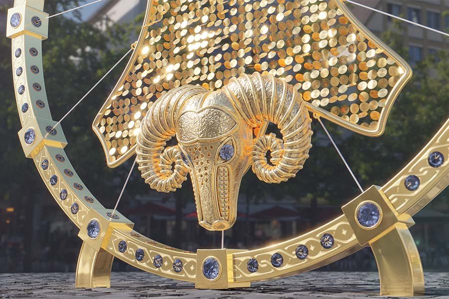 golden ram head sculpture with reflective discs in a kinetic art installation