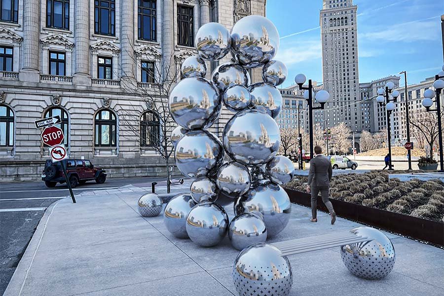 Reflective stainless-steel sphere sculpture in an urban plaza