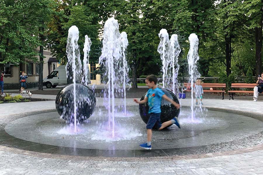 Programmable fountain system with illuminated water jets and granite sphere elements in a landscaped park