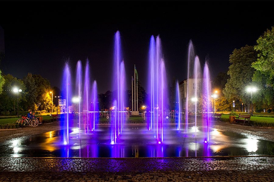 purple illuminated fountain jets in city park