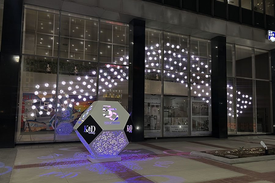 Public kinetic light installation with suspended glowing spheres and geometric sculpture