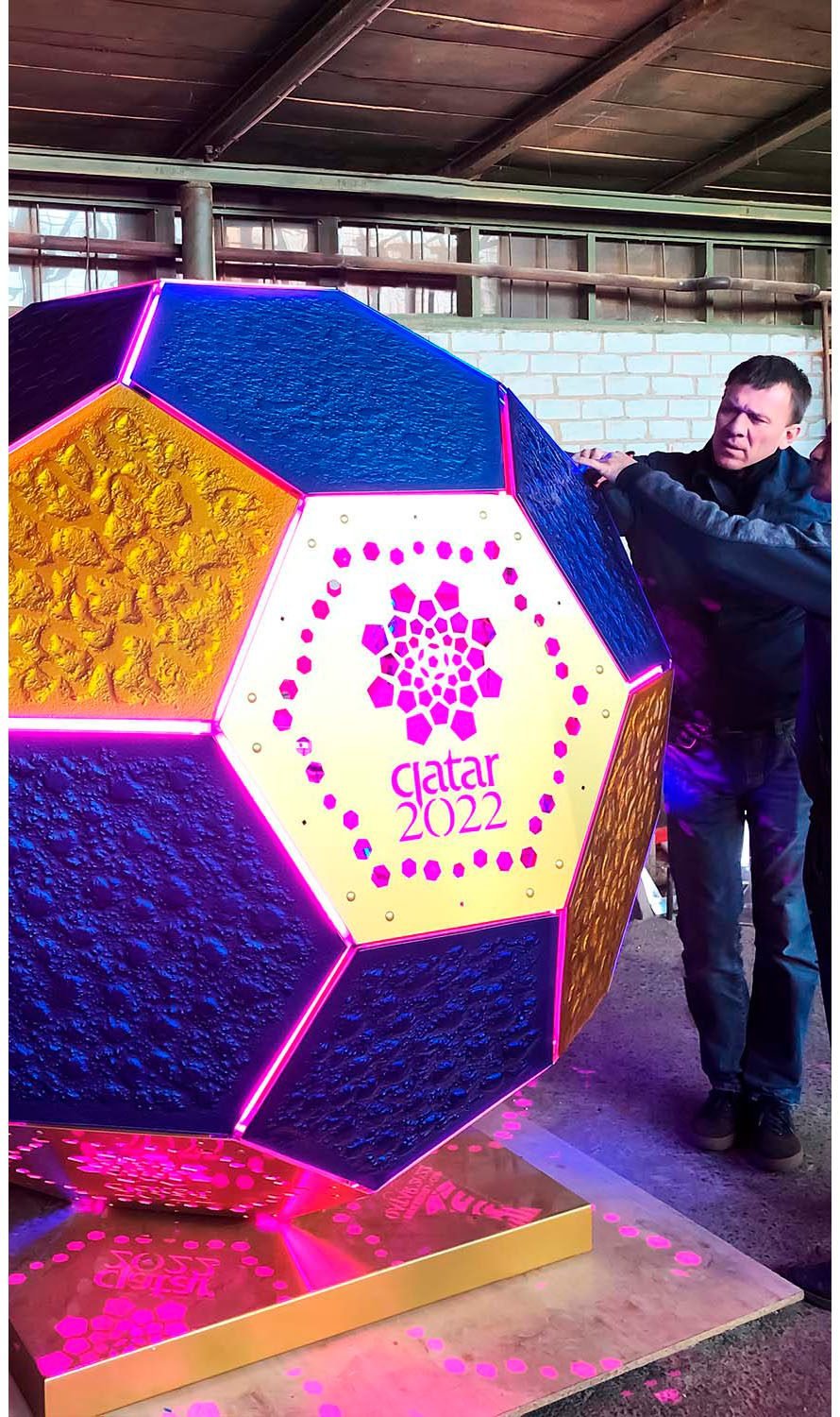 Workers DION installing illuminated decorative panels on a geometric sculpture for Qatar 2022